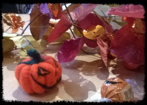 A felted pumpkin grinning at a chocolate pumpkin